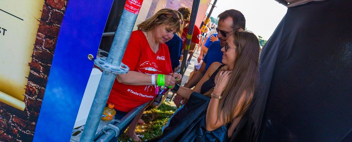 de ingang van een festival waar iemand van de crew net een polsbandje aandoet bij een bezoeker